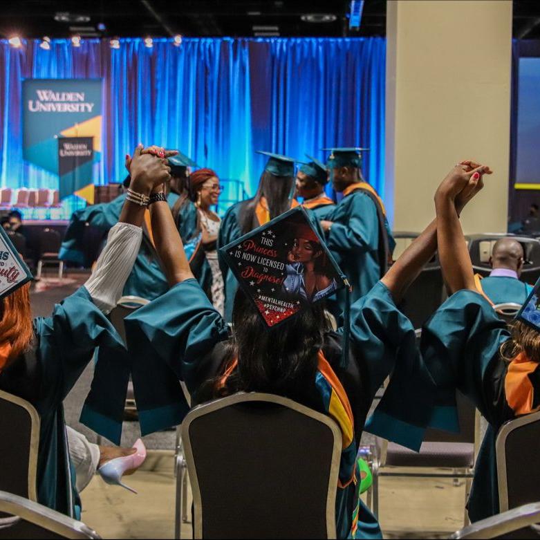 Walden graduates holding hands up at ceremony