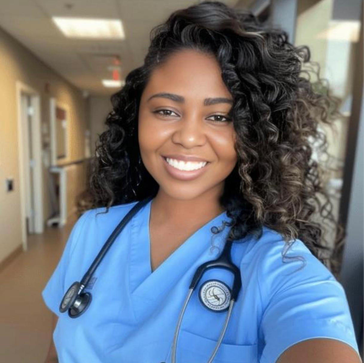 Woman in blue scrubs posing in medical hallway