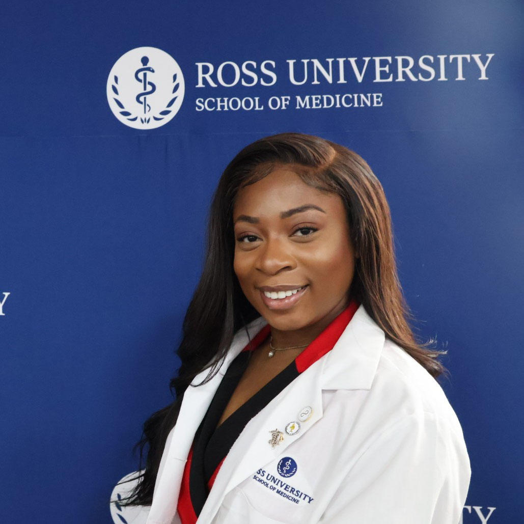 Lesley Azike, posing in front of Ross University banner