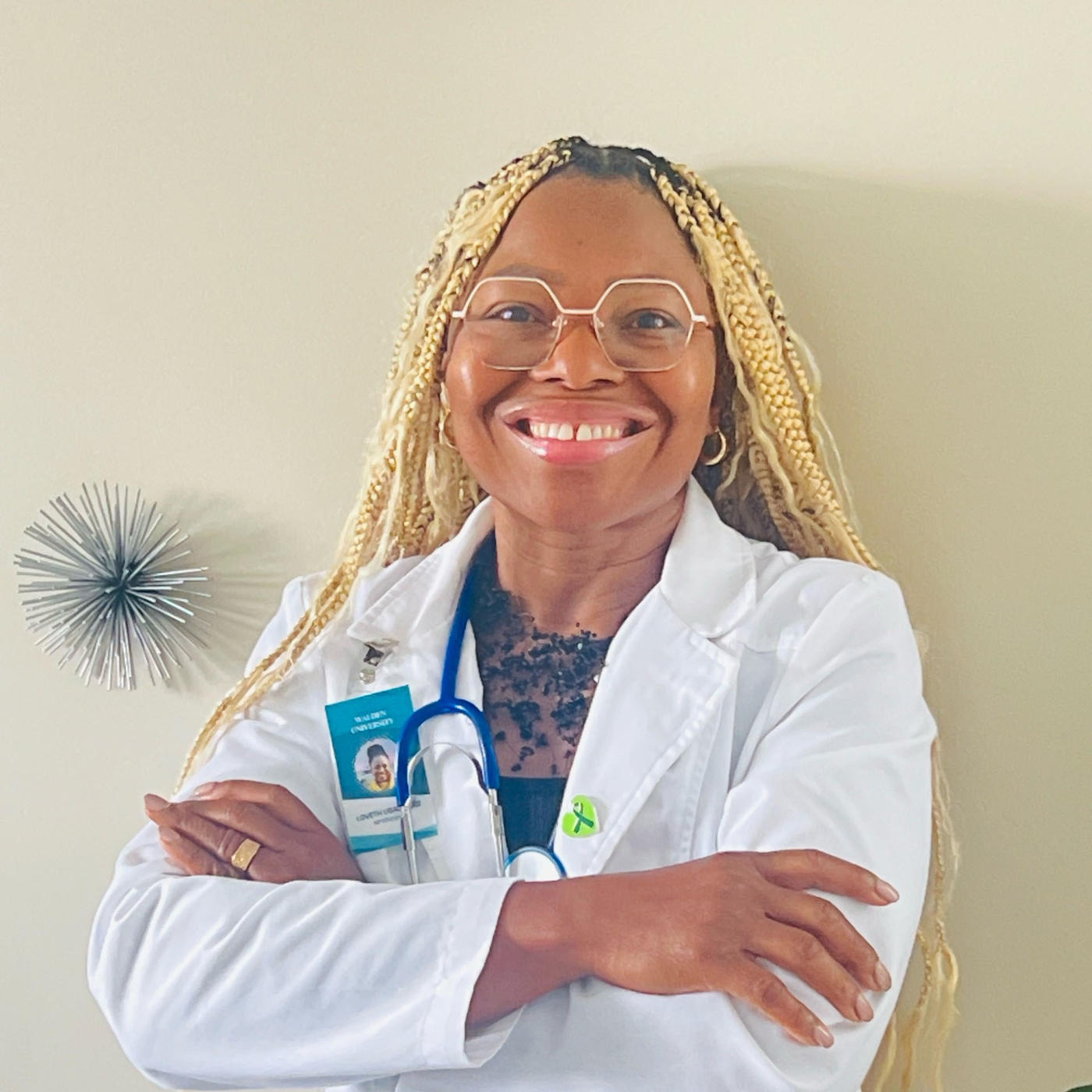 Woman in white lab coat smiling with crossed arms